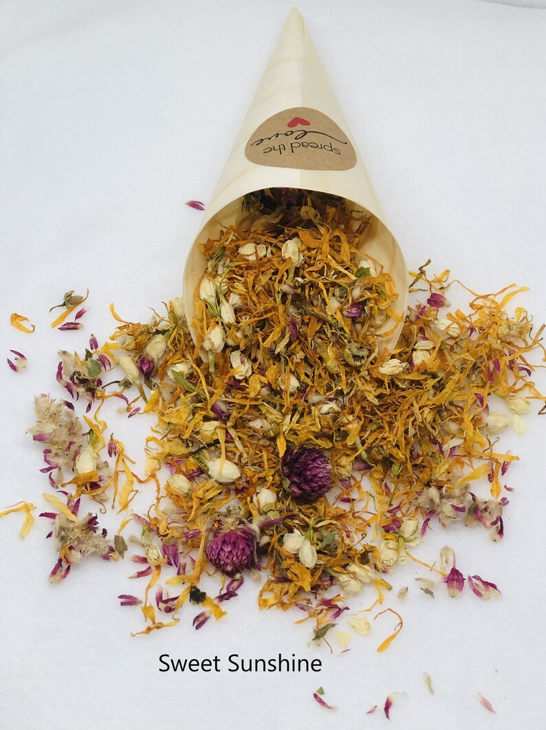 May include: A cone filled with dried flower petals, including yellow, orange, white, and purple petals. The cone is labeled "Spread the Love". The petals are scattered on a white surface with the text "Sweet Sunshine".