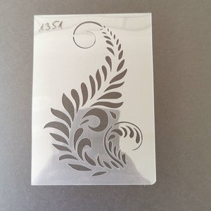 May include: A clear plastic stencil featuring a decorative fern design. The stencil is labelled "1351".