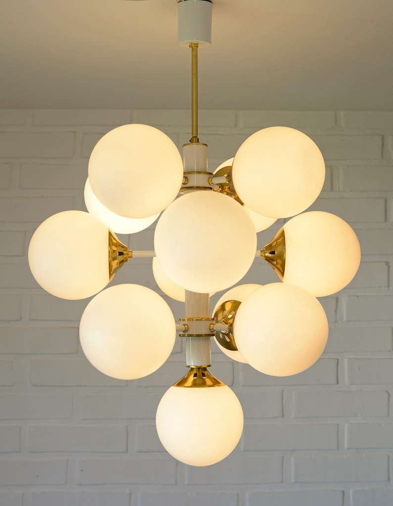 May include: A white and gold modern chandelier with 10 round frosted glass globes.