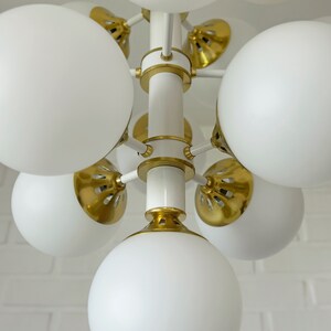 May include: A white and gold modern chandelier with multiple round white glass shades.