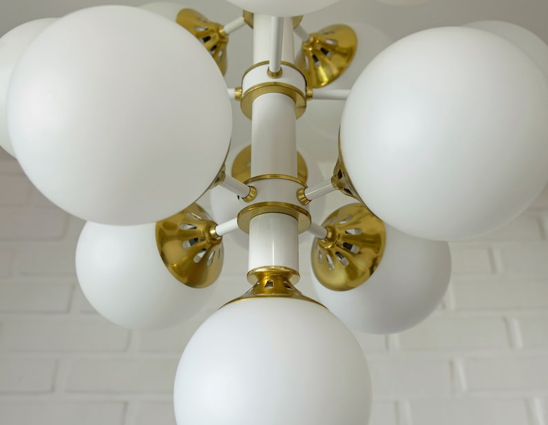 May include: A white and gold modern chandelier with multiple round white glass shades.