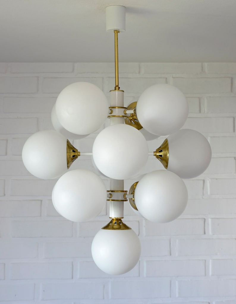 May include: A white and gold modern chandelier with multiple white globe-shaped light fixtures.