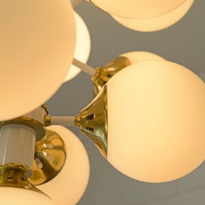 May include: A modern gold and white chandelier with multiple round frosted glass globes.