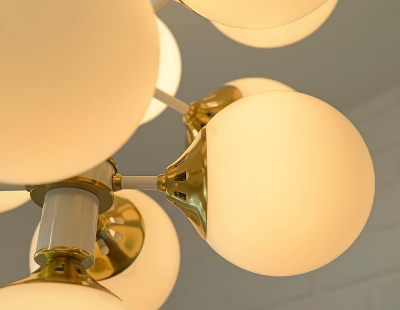 May include: A modern gold and white chandelier with multiple round frosted glass globes.