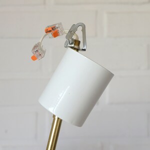 May include: Close-up of a white ceiling fixture with a gold metal rod and wire connectors labeled "WAGO 222".