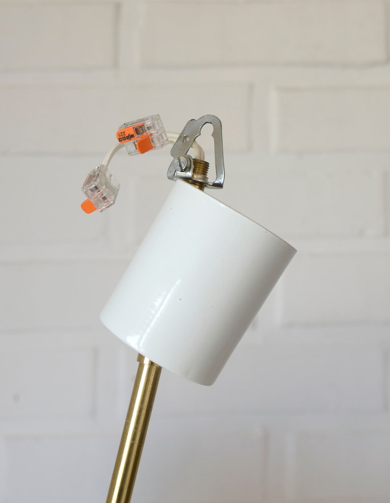 May include: Close-up of a white ceiling fixture with a gold metal rod and wire connectors labeled "WAGO 222".