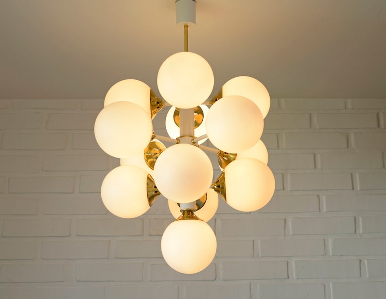May include: A white ceiling light fixture with multiple round, white frosted glass bulbs. The fixture is made of gold metal and has a modern design.