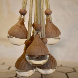 May include: A set of six wooden car air fresheners with clear glass inserts. The fresheners are hanging from beige cords with wooden beads.
