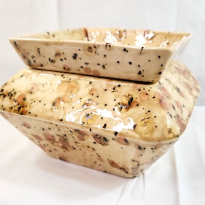 May include: A square ceramic planter with a speckled brown and beige glaze. The planter has a removable top that is also square and speckled.