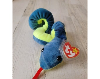 Pode incluir: Uma cobra Ty Beanie Baby azul e verde com uma língua vermelha e uma estrela amarela na etiqueta. A etiqueta diz "Beanie Babies".
