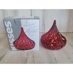 Può includere: Piatto per caramelle in cristallo rosso a forma di bacio Hershey's. Il piatto è coperto e ha un coperchio. La scatola dice "Crystal Kiss Covered Candy Dish Ruby Crystal".