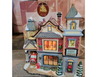 May include: A ceramic fire station village scene with a red fire truck, a lit window, and a sign that reads "Fire Station".
