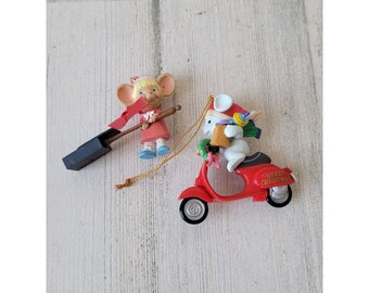 May include: Two Christmas ornaments featuring a red scooter with a white mouse wearing a Santa hat and a red and white mouse holding a broom. The scooter ornament has the text "Merry Christmas" on the side.