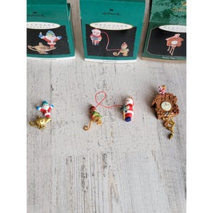 May include: Set of five Hallmark Keepsake Christmas ornaments. The ornaments feature a monkey, Santa Claus, a genie lamp, a string of lights, and a cuckoo clock.