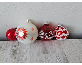 May include: Four vintage Christmas baubles, two red glass baubles with white designs, one white glass bauble with red and white designs, and one red glass bauble with white crocheted trim.