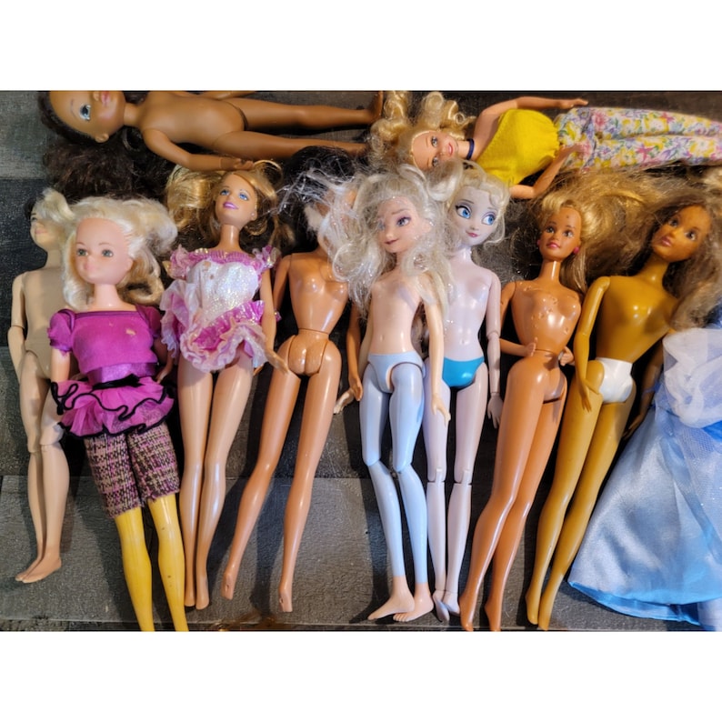 May include: A collection of ten dolls with various hairstyles and outfits. The dolls are all wearing different colored dresses and have different hair colors. Some of the dolls are wearing accessories, such as earrings and necklaces.