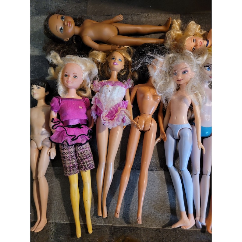 May include: A collection of vintage dolls with different hairstyles and outfits. The dolls are made of plastic and have painted faces. Some of the dolls are wearing dresses, while others are wearing pants and shirts. The dolls are all in good condition and would be a great addition to any doll collection.