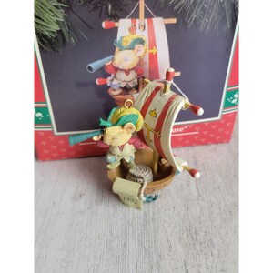 May include: A vintage 1992 Christmas ornament featuring two mice dressed as sailors on a small sailboat. The ornament is made of painted resin and has a red, white, and blue color scheme.