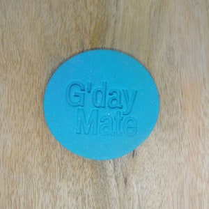 May include: A round, blue, glittery, playdough-like object with the words "G'day Mate" embossed on the surface.