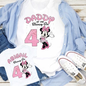 Puede incluir: Camisetas blancas con texto rosa y gr&aacute;ficos de Minnie Mouse. Una camiseta dice "DADDY of the Birthday Girl" con el n&uacute;mero 4. La otra camiseta dice "ABIGAIL Birthday Girl" con el n&uacute;mero 4. Las camisetas est&aacute;n sobre una camisa azul claro y vaqueros.