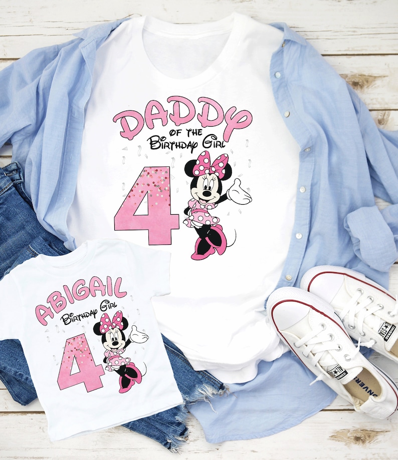 Puede incluir: Camisetas blancas con texto rosa y gr&aacute;ficos de Minnie Mouse. Una camiseta dice "DADDY of the Birthday Girl" con el n&uacute;mero 4. La otra camiseta dice "ABIGAIL Birthday Girl" con el n&uacute;mero 4. Las camisetas est&aacute;n sobre una camisa azul claro y vaqueros.