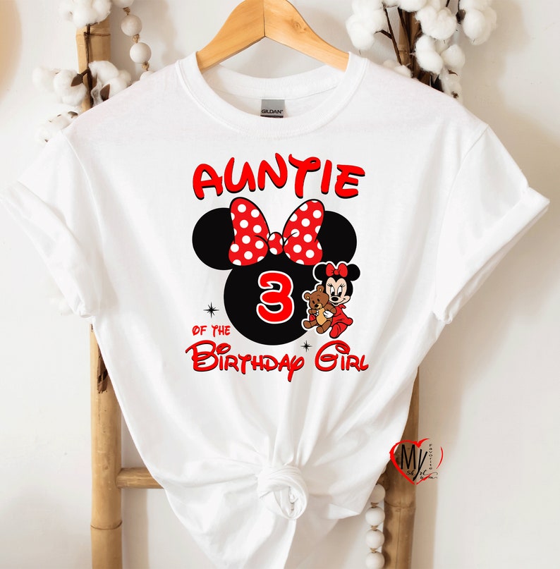 May include: White t-shirt with red text that says "Auntie of the Birthday Girl" with a black and red Minnie Mouse head and a number 3.  Minnie Mouse is holding a brown teddy bear.