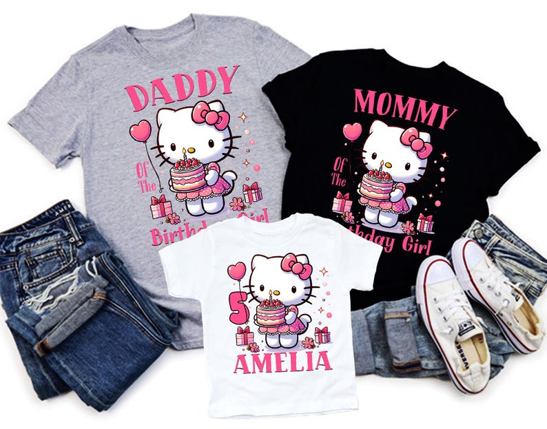 May include: Three t-shirts featuring a Hello Kitty design, ideal for a birthday. The shirts are grey, black, and white, with pink text and graphics. The grey shirt says "Daddy of the Birthday Girl." The black shirt says "Mommy of the Birthday Girl." The white shirt says "5 Amelia."