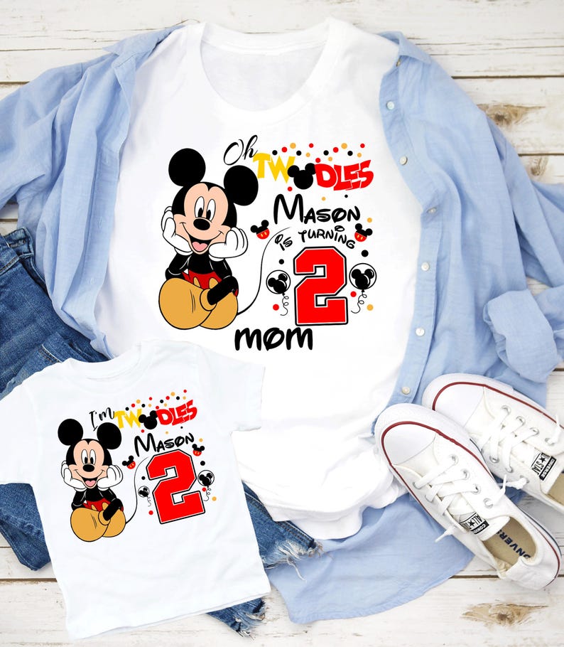 May include: White t-shirts with a Mickey Mouse graphic and the text "Oh Twodles Mason is turning 2 mom" and "I'm Twodles Mason 2". The shirts are paired with blue jeans, a light blue button-down shirt, and white sneakers.