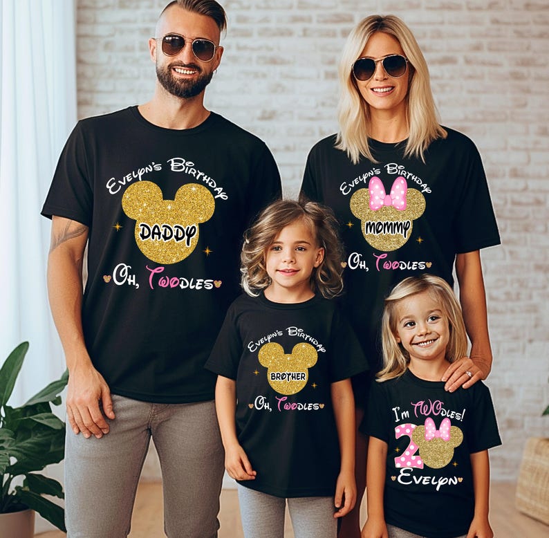 Puede incluir: Una familia de cuatro personas con camisetas negras con orejas de Mickey Mouse de purpurina dorada y texto que dice "Evelyn's Birthday", "Daddy", "Mommy", "Brother", "Oh, Toodles", y "I'm Toodles! Evelyn".