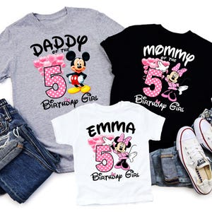 Puede incluir: Tres camisetas con gr&aacute;ficos de Disney. Una camiseta gris dice "Daddy of the 5th Birthday Girl" con Mickey Mouse. Una camiseta negra dice "Mommy of the 5th Birthday Girl" con Minnie Mouse. Una camiseta blanca dice "Emma 5th Birthday Girl" con Minnie Mouse.