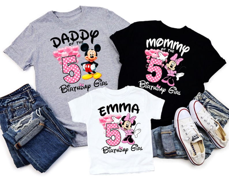 Puede incluir: Tres camisetas con gr&aacute;ficos de Disney. Una camiseta gris dice "Daddy of the 5th Birthday Girl" con Mickey Mouse. Una camiseta negra dice "Mommy of the 5th Birthday Girl" con Minnie Mouse. Una camiseta blanca dice "Emma 5th Birthday Girl" con Minnie Mouse.