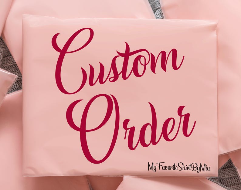 May include: A pale pink package with the words "Custom Order" in a burgundy script font. The text "My Favorite Shirt By Mia" is at the bottom in a smaller, black font. The package is sealed.