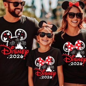 May include: Three black t-shirts featuring a white and red graphic of a castle, fireworks, and the text Disney 2026. The shirts display either a Mickey Mouse or Minnie Mouse ear design with a red polka dot bow on the Minnie versions.