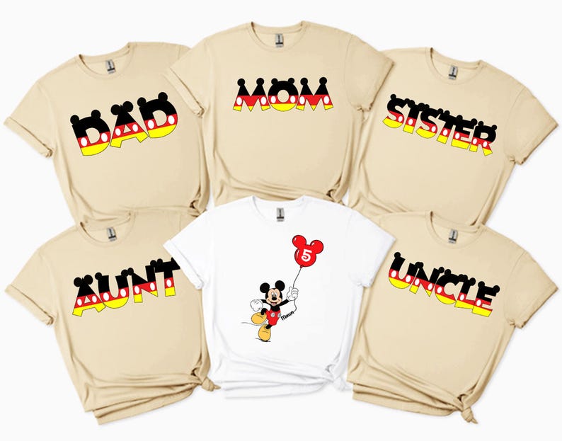 May include: A selection of beige and white t-shirts with Mickey Mouse designs. The shirts display the words "DAD", "MOM", "SISTER", "AUNT", and "UNCLE" in a black, red, yellow, and white font. One shirt features a Mickey Mouse graphic holding a balloon.
