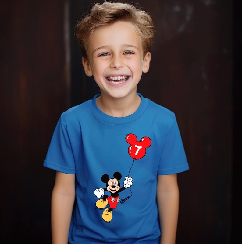 May include: A blue t-shirt with a Mickey Mouse design holding a red balloon with the number 7. The shirt has a round neck and short sleeves. The name "Oliver" is printed on the shirt.