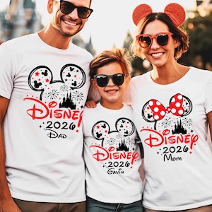 May include: Three white t-shirts featuring a black Mickey Mouse ear silhouette filled with red stars and fireworks. The design includes the red text Disney, the year 2026, and the names Dad, Gavin, and Mom. The shirts feature a castle graphic.