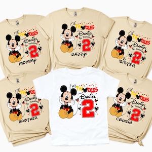 May include: A collection of beige and white t-shirts featuring a Mickey Mouse graphic. Each shirt has the text "Oh Twodles, Daniel is turning 2" with a family member's title: Mommp, Daddy, Sister, Brother, or Cousin.