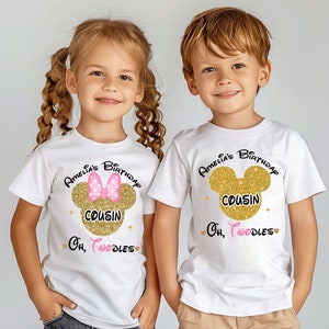 Puede incluir: Dos camisetas blancas con orejas de Mickey Mouse de purpurina dorada y el texto "Amelia's Birthday Cousin Oh, Toodles". La camiseta de la ni&ntilde;a tiene un lazo rosa en las orejas de Mickey Mouse.