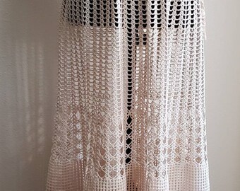 May include: A long, cream-colored crochet skirt with a delicate floral pattern. The skirt is made of a lightweight, airy fabric and has a flowing silhouette.