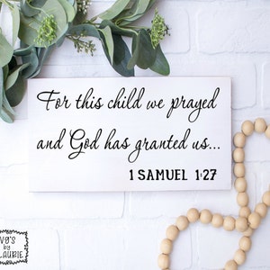 Puede incluir: Un letrero de madera blanco con texto negro que dice "For this child we prayed and God has granted us... 1 SAMUEL 1:27".