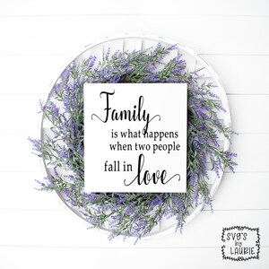 May include: A white wooden sign with black text that reads "Family is what happens when two people fall in love." The sign is surrounded by a wreath of purple flowers.