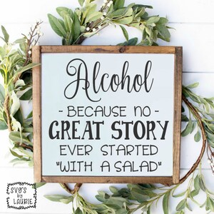 Può includere: Un cartello con cornice in legno con le parole "Alcohol - BECAUSE NO - GREAT STORY EVER STARTED "WITH A SALAD"" in lettere nere su sfondo azzurro. Il cartello è circondato da fogliame verde.