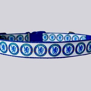 May include: A blue and white dog collar with the Chelsea Football Club emblem. The collar has a blue buckle and a repeating pattern of the team's logo. The collar is approximately 2.5 cm wide.