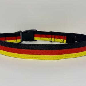 Op de afbeelding: Zwarte hondenriem met gele, rode en zwarte strepen, die lijken op de Duitse vlag.