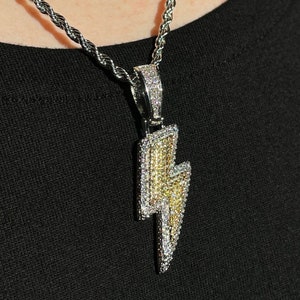 May include: A silver chain necklace with a large, diamond-encrusted lightning bolt pendant.