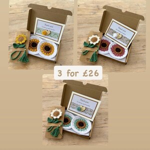 May include: Three gift boxes containing crochet sunflower bookmarks and two round crochet coasters each. The bookmarks feature green stems and tassels. Each box includes a card with the text Thank you for being a great teacher.