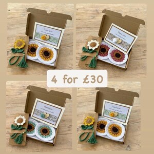 May include: Four brown cardboard gift boxes containing crochet sunflower-themed items. Each box includes a crochet sunflower bookmark with a green tassel and two round crochet sunflower coasters. Each box features a thank you card with a small heart.