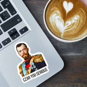May include: A sticker featuring a portrait of a man in a military uniform with the text "CZAR YOU SERIOUS" printed below. The sticker is on a laptop computer.