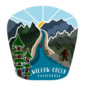 May include: A colourful illustration depicting a river scene with a kayaker, mountains, trees, and a Bigfoot silhouette. The text "Willow Creek California" is displayed in white. The design has a sunny sky and a vibrant colour palette.