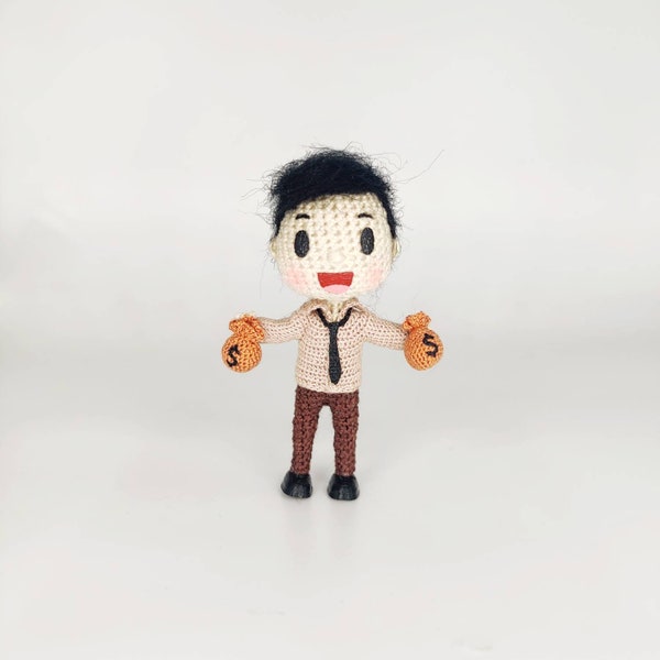 Amigurumi tiny boy with money bag in hand Young banker with black hair Office worker